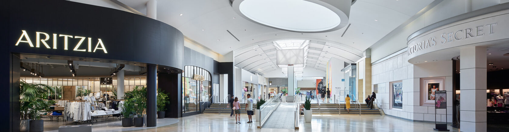 Spacious mall walkway with accessible paths and shoppers moving through popular retail areas
