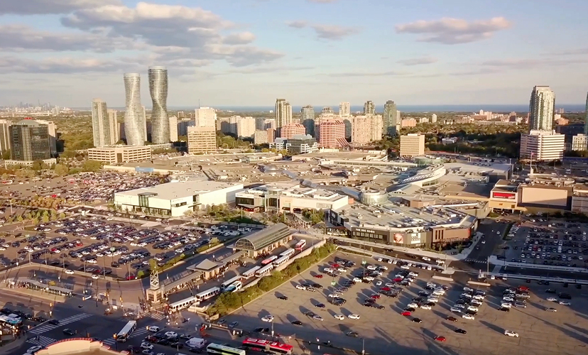 Aerial view of the shopping centre with a large parking area and surrounding city skyline