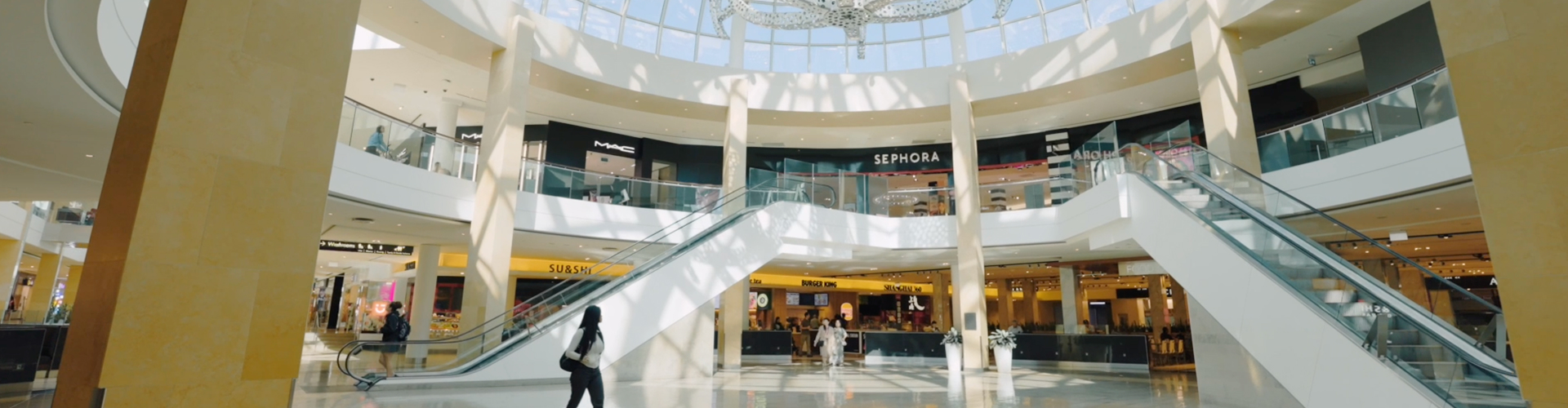 Shopping centre interior featuring escalators and retail stores including Sephora