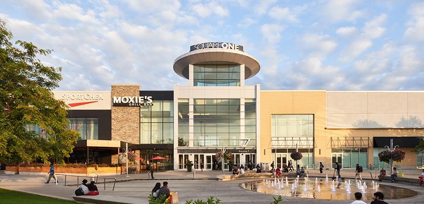 Square One mall entrance with security presence and shoppers in outdoor plaza area