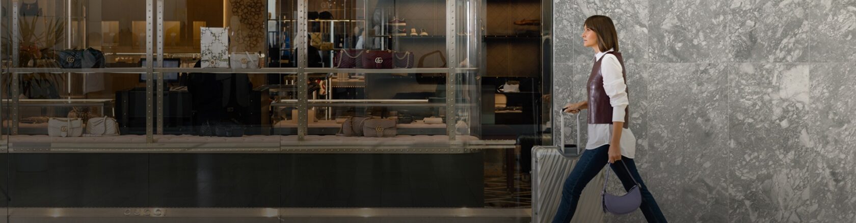 Visitor walking through the shopping centre with luggage and bags near multiple retail stores