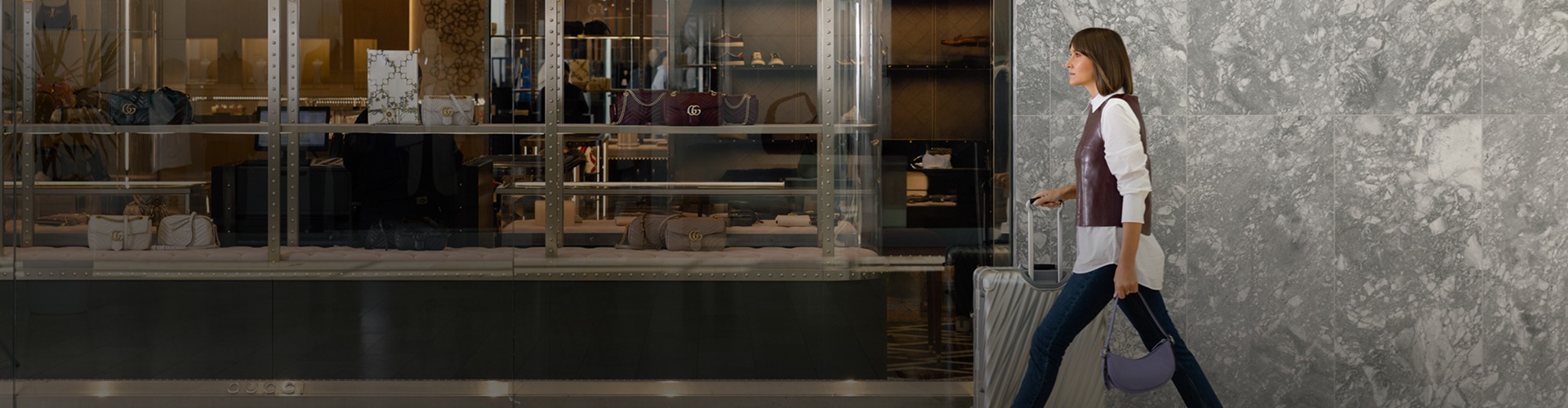 Visitor walking through the shopping centre with luggage and bags near multiple retail stores