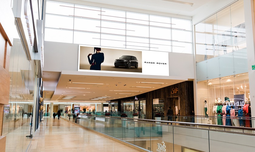 Shopping centre interior featuring digital screens with shoppers viewing media content