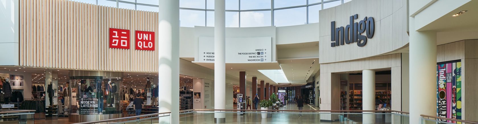 Shoppers exploring stores like Uniqlo and Indigo in a busy and well-designed mall interior