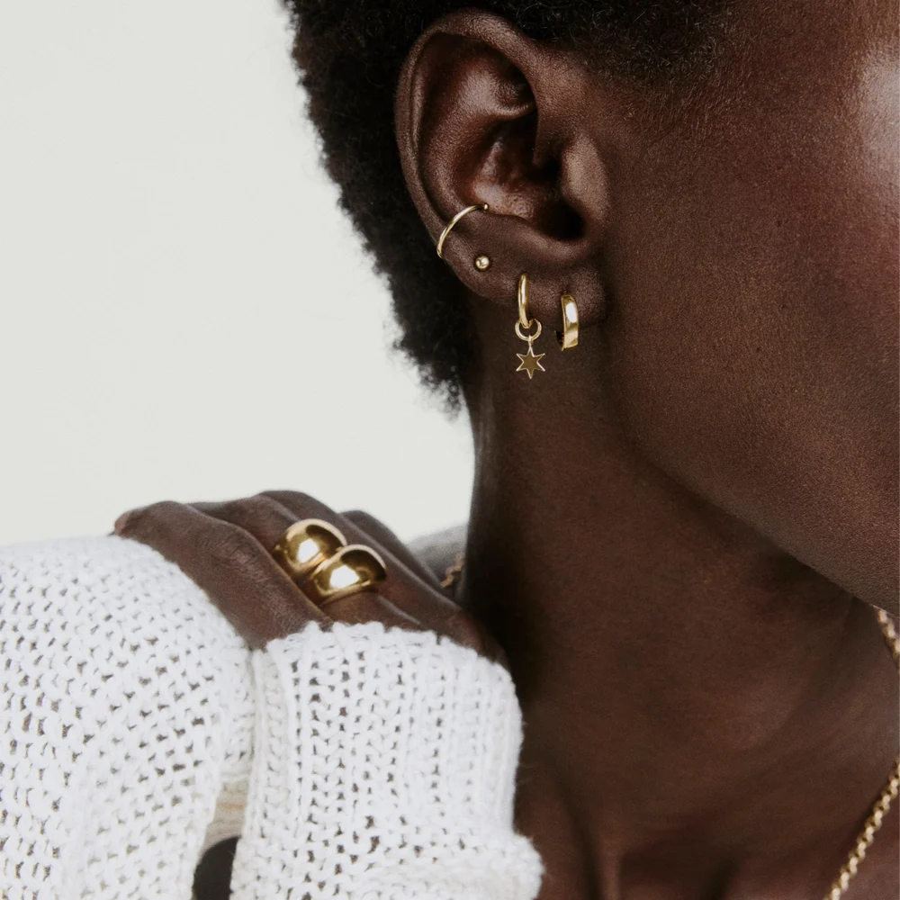 A woman wearing gold earrings and rings
